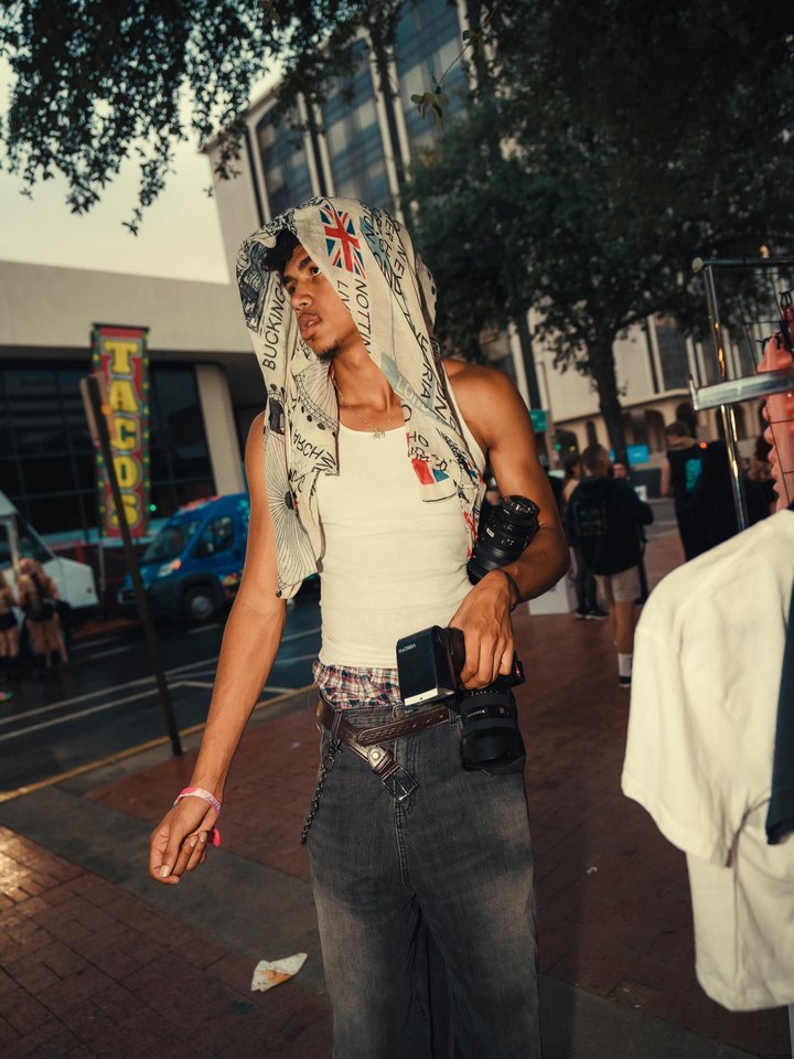 Jonathan Platt on a city street with a scarf over his head, holding two cameras